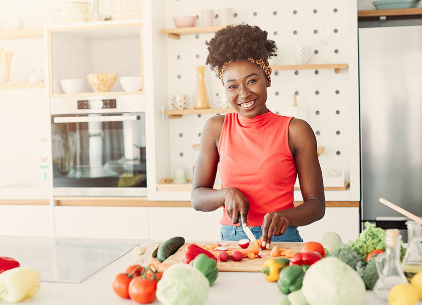 smiling african american woman cutting up vegetables