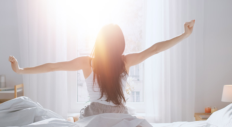 woman sitting up in bed and stretching