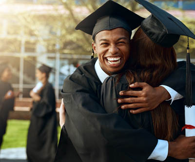 Black college graduate hugging his mom