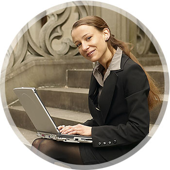 Photo of employee enrolling in their benefits on their laptop while sitting on some steps outside